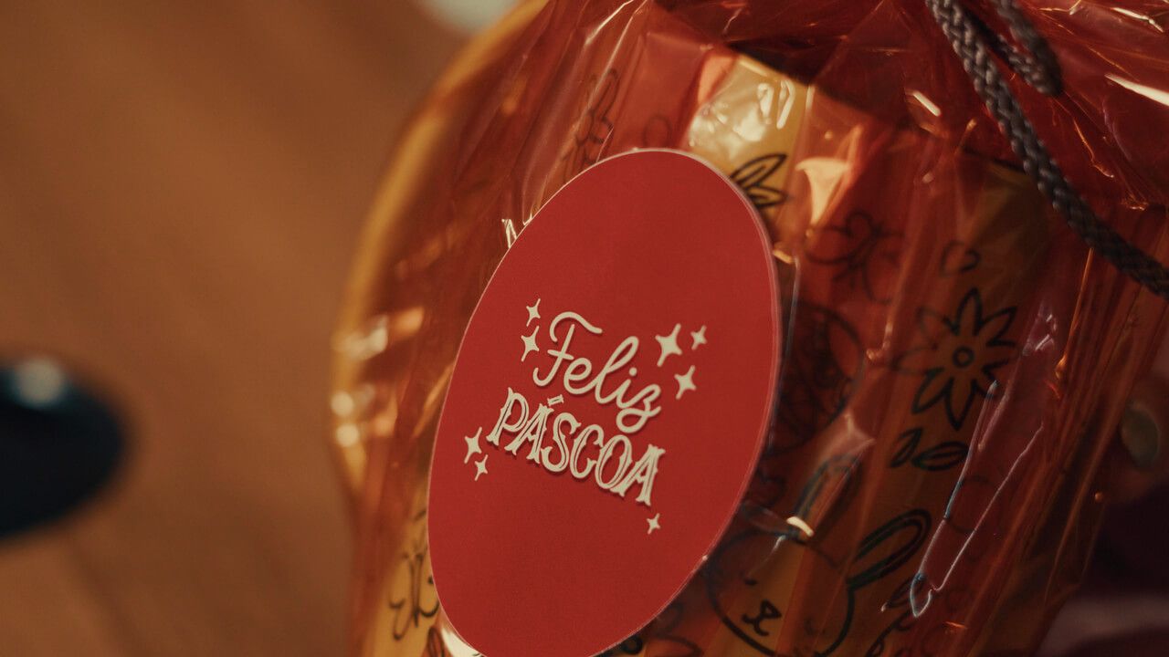 Adesivo oval personalizado Feliz Páscoa aplicado em embalagem de chocolate para venda sazonal.