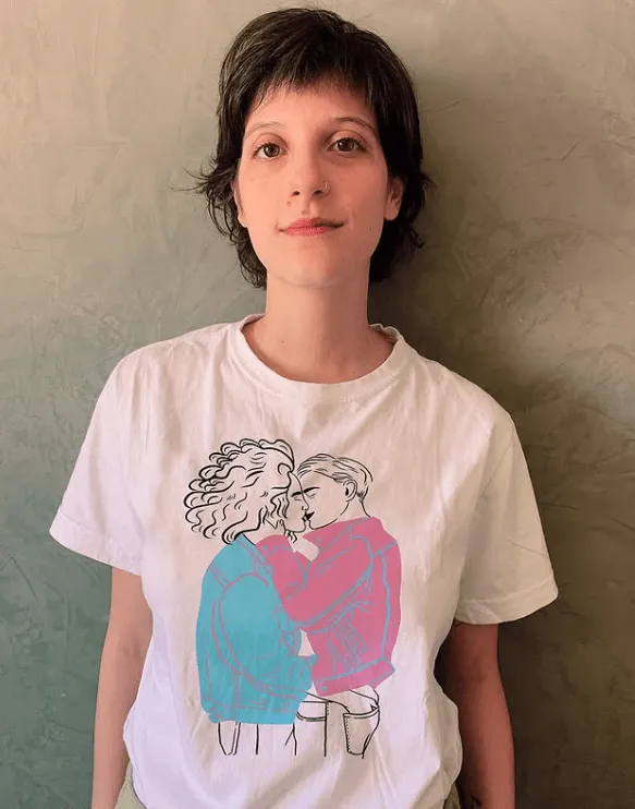 Retrato da ilustradora Sophia Andreazza, criadora do santinho “Fernanda da Sorte” utilizado no Globo de Ouro, usando camiseta com ilustração.