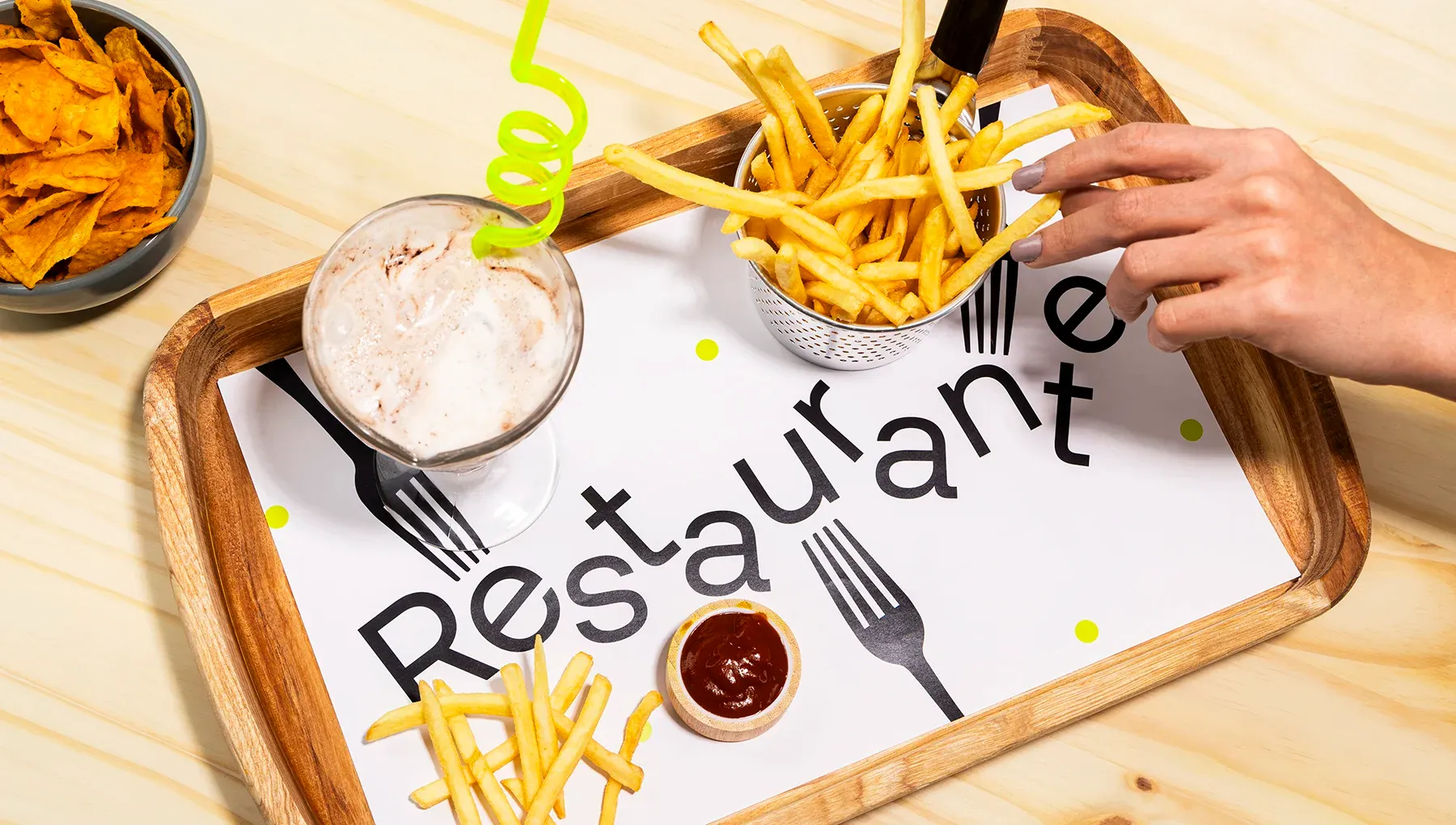 Jogo americano de papel para restaurante servido em uma bandeja de madeira com batata frita, molho, milk-shake e petiscos, destacando o uso prático no dia a dia.